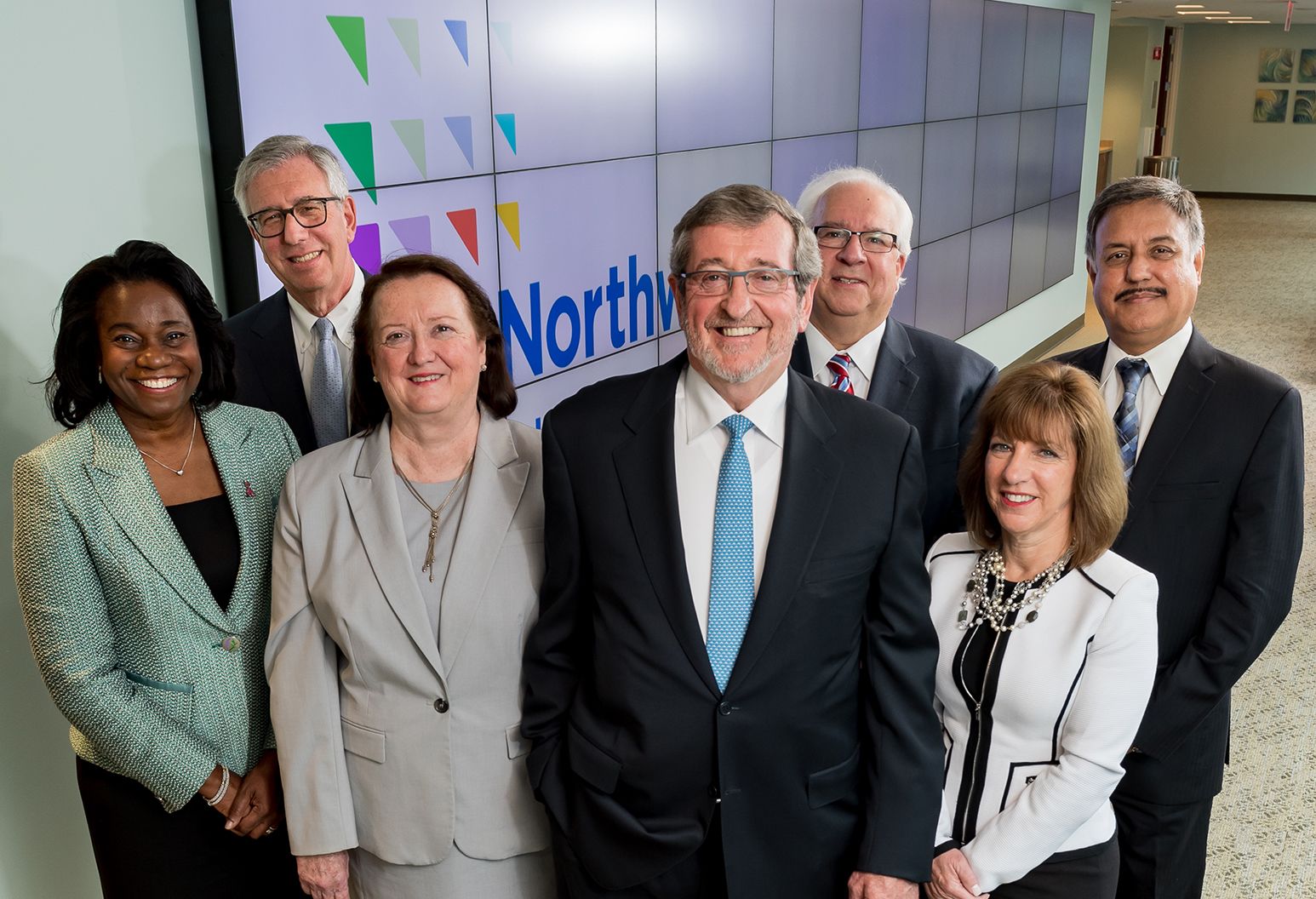 A group of Northwell Health senior leaders stand in front of a digital display that reads Northwell Health.